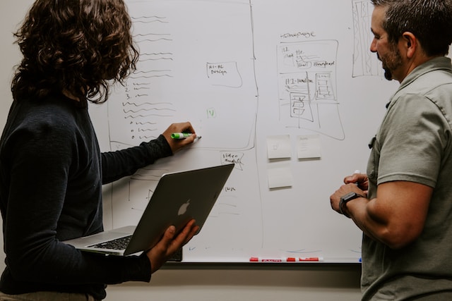 two guys working and writing on white board